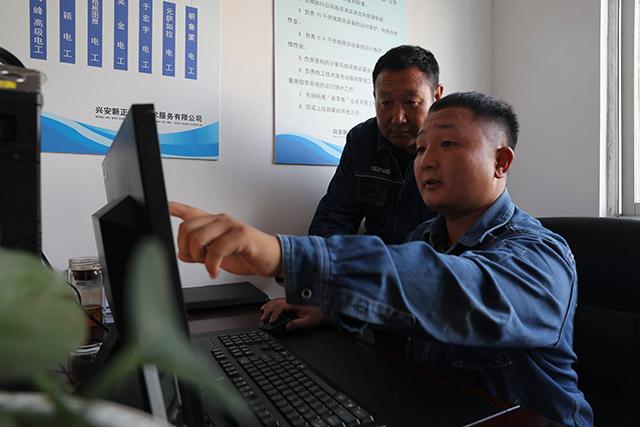 兒子為父親講解電腦上辦理業務。畢力格攝