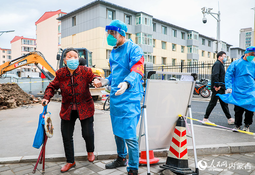 呼和浩特市玉泉區一處核酸篩查點,黨員志愿者幫助行動不便的老人前往核酸檢測點進行采樣。丁根厚攝