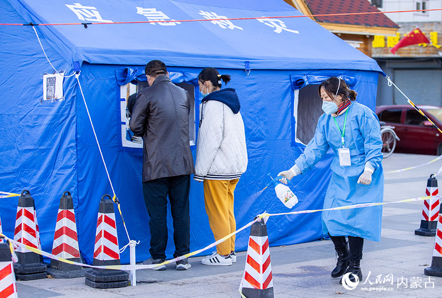 呼和浩特市玉泉區一處核酸篩查點,社區工作者對核酸采樣現場進行消殺。丁根厚攝