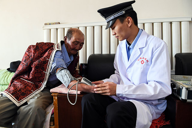 算井子邊境派出所的衛生員陳亞偉(右)給牧民黨德爾進行體檢。