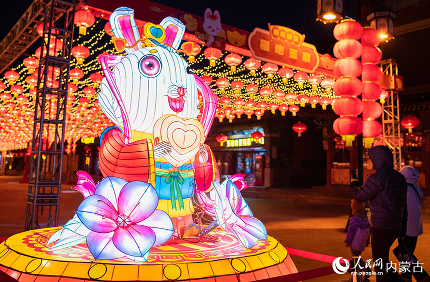 1月18日晚，游客從呼和浩特市玉泉區(qū)塞上老街歷史文化街區(qū)“玉兔”花燈旁經(jīng)過。丁根厚攝