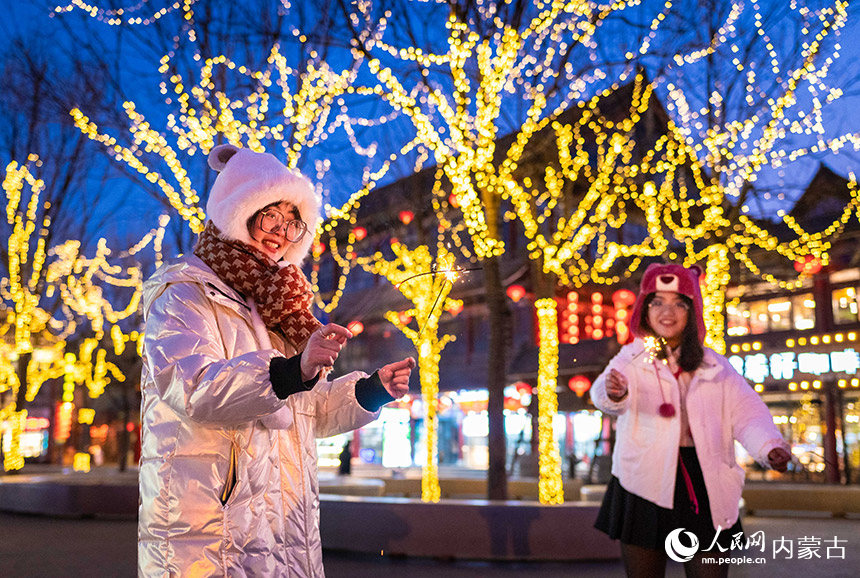 1月18日晚，游客手持煙花棒在呼和浩特市玉泉區塞上老街歷史文化街區彩燈樹下游玩。丁根厚攝