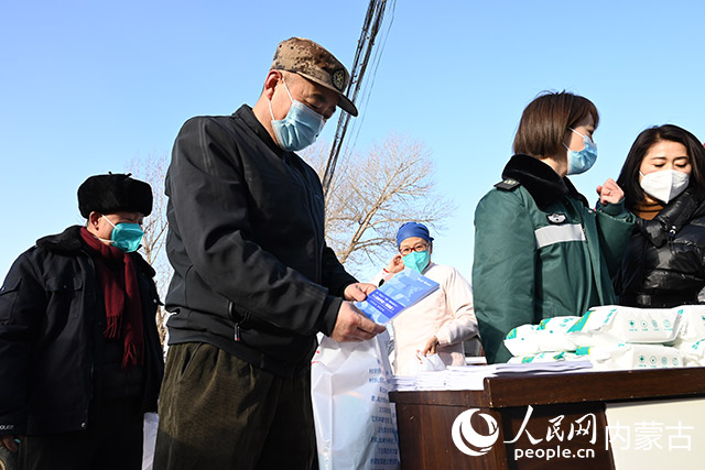 村民領取防疫物資及人民網編寫的防疫手冊。人民網 劉藝琳攝