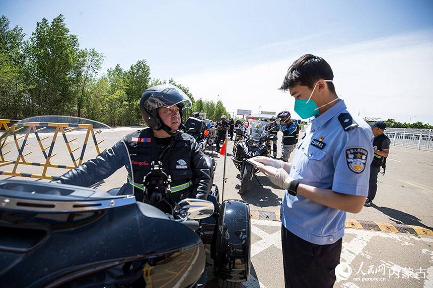 二連出入境邊防檢查站執勤民警查驗自駕旅游團成員通關證件。胡富國攝