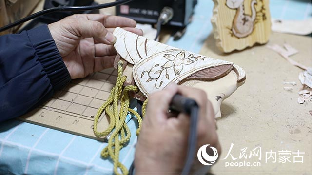 蘇殿政對朽木粘畫進行燙畫工藝處理。孟佳澍攝