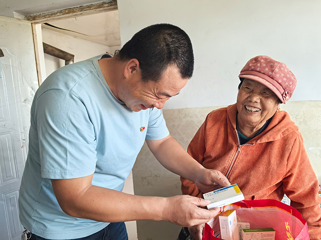 圖為9月12日,內(nèi)蒙古化德縣崩巴圖村黨支部書記李國(guó)成(圖左)為70多歲的戈玉蘭老人從縣里帶來藥。記者 張棖攝