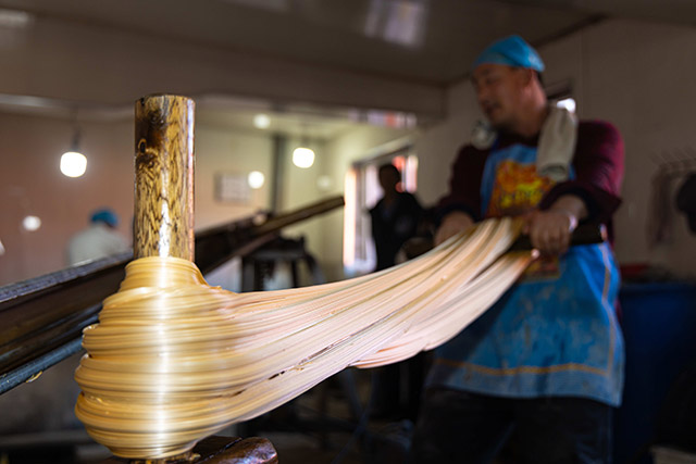 “麻糖”在黑城村拉糖師傅的反復(fù)疊拉下變得層次分明。烏力更攝