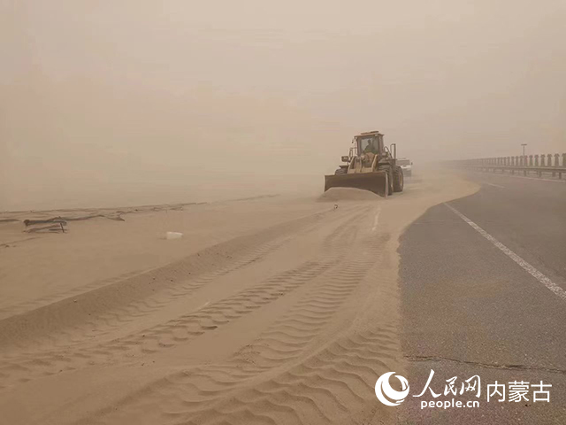 受沙塵天氣影響,阿拉善盟策克至達來呼布一級公路出現沙阻。達來呼布機械化邊防養護隊迎風而動,采取人工配合機械的方式快速清理路面積沙。趙巍 攝
