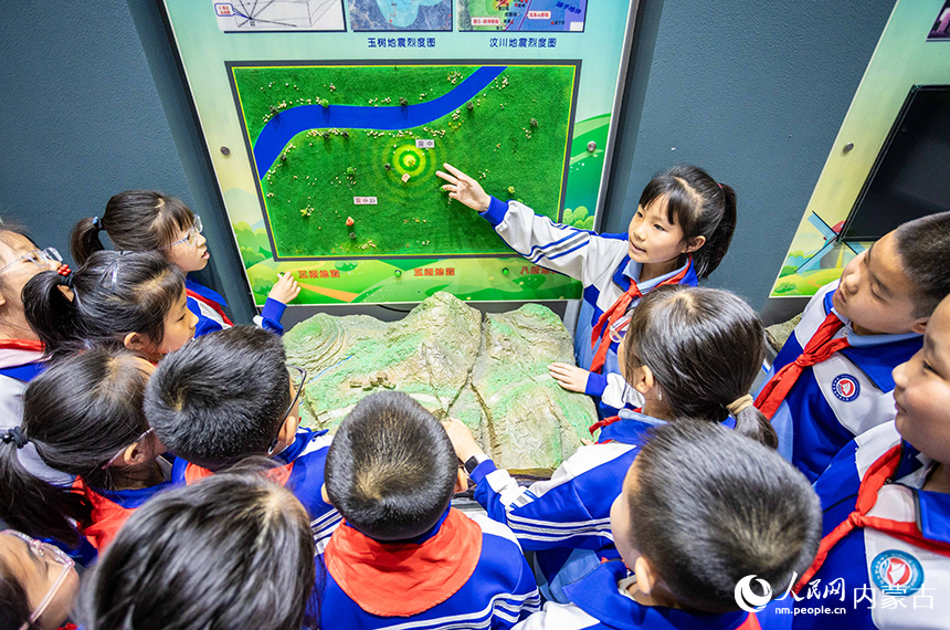 內蒙古呼和浩特市玉泉區通順街小學學生在地震科普館通過演示裝置了解地震知識。丁根厚攝