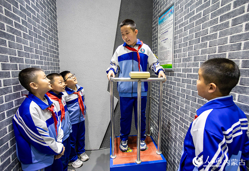 內蒙古呼和浩特市玉泉區通順街小學學生在地震科普館內體驗“地震小屋”。丁根厚攝