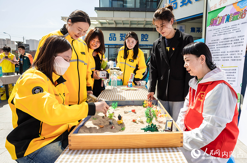 外賣員在呼和浩特市玉泉區(qū)“‘新’心攜手 基層共治”游園會活動現(xiàn)場體驗沙盤游戲療法。丁根厚攝