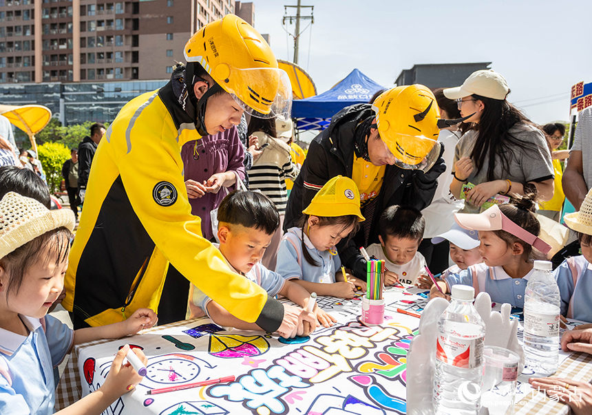 社區居民和外賣員在呼和浩特市玉泉區“‘新’心攜手 基層共治”游園會活動現場共同參與“友好儷城”涂鴉。丁根厚攝