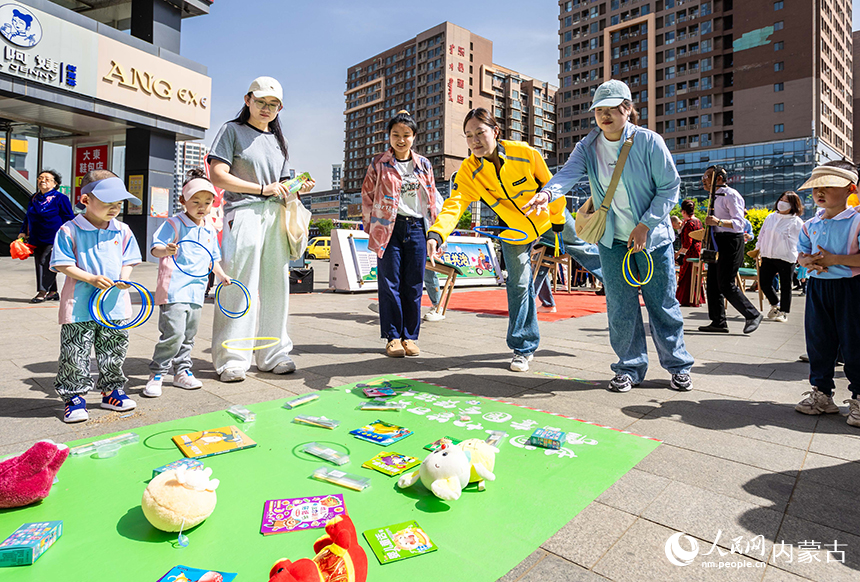 社區(qū)居民和外賣員在呼和浩特市玉泉區(qū)“‘新’心攜手 基層共治”游園會活動現(xiàn)場參加套圈游戲。丁根厚攝