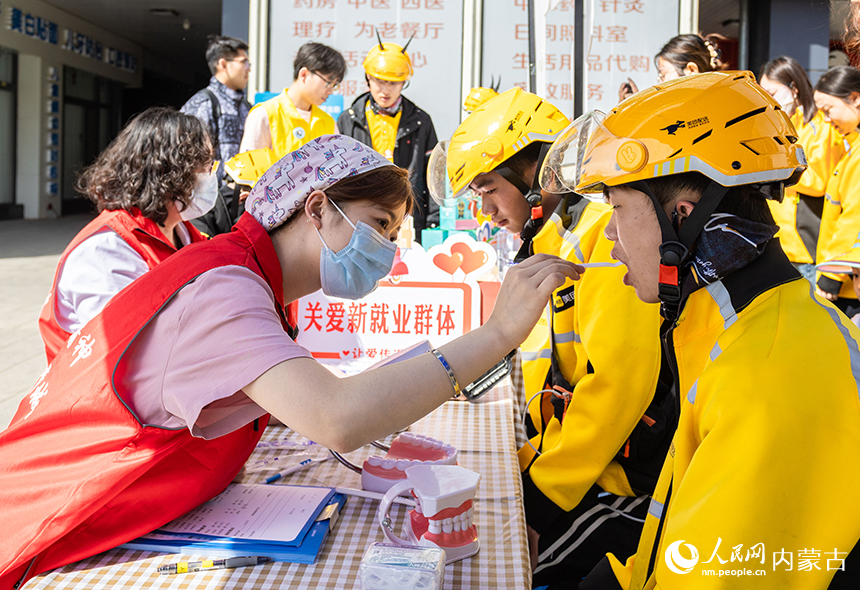 醫務志愿者在呼和浩特市玉泉區“‘新’心攜手 基層共治”游園會活動現場為外賣員進行口腔檢查。丁根厚攝