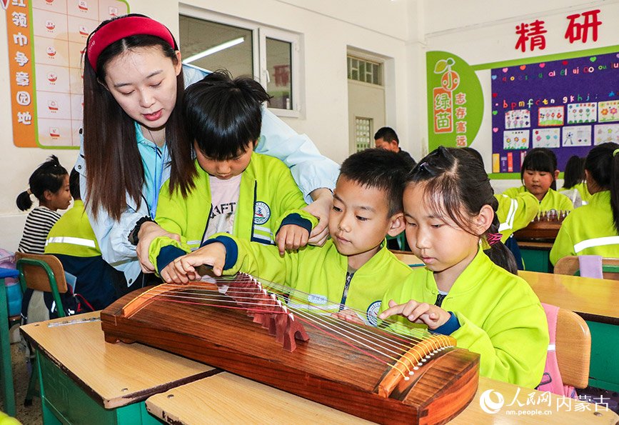 5月23日,呼和浩特市玉泉區青少年宮“流動少年宮”公益專列校園活動現場,學生在樂韻潤心藝啟成長古箏課上學習彈奏技藝。丁根厚攝