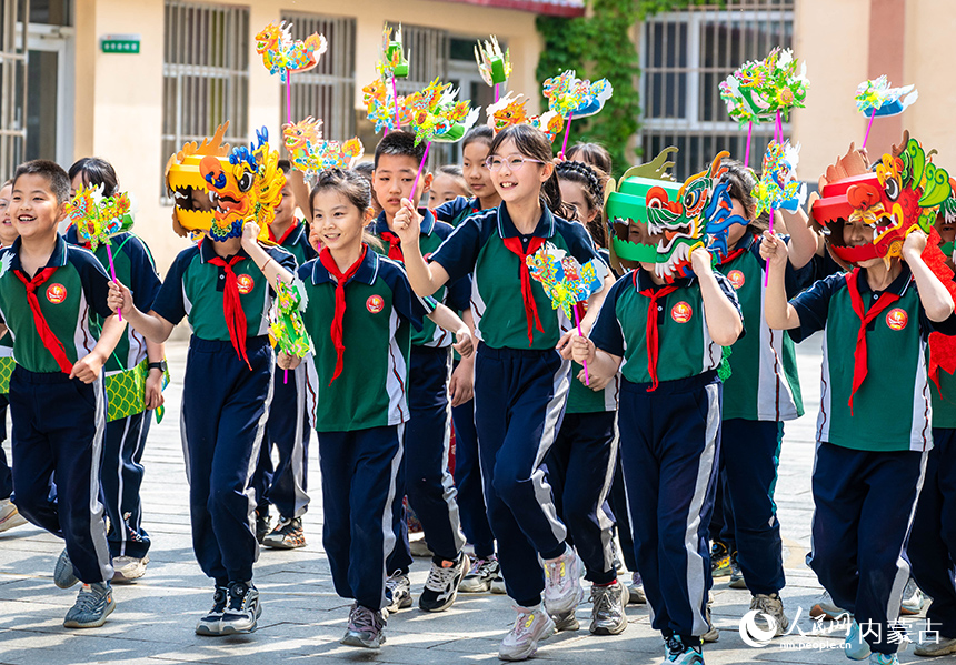 內蒙古呼和浩特市玉泉區恒昌店巷小學學生在“繽紛端午 粽享童趣”主題活動現場參加趣味龍舟風車賽。丁根厚攝