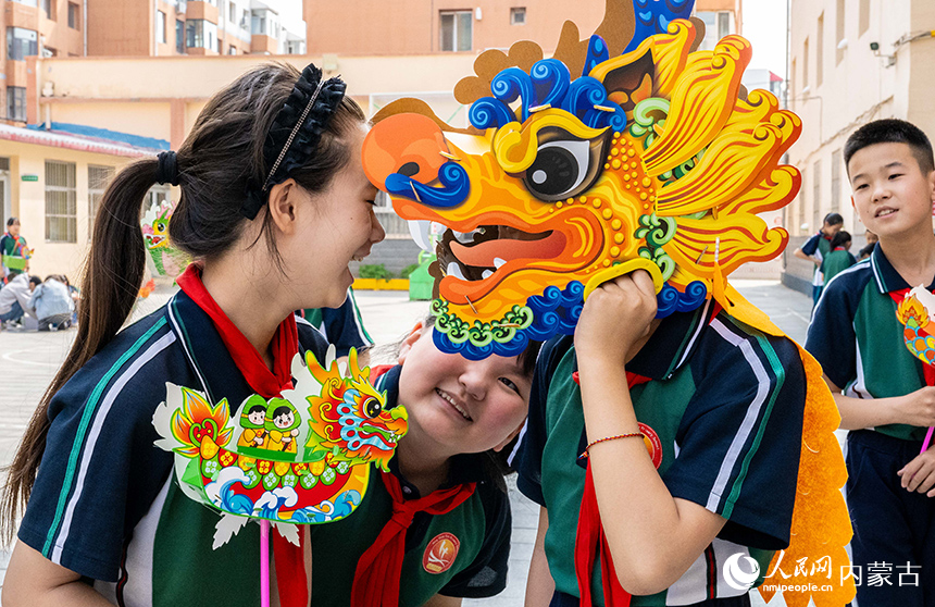 內蒙古呼和浩特市玉泉區恒昌店巷小學學生們在趣味龍舟風車賽比賽現場互動。丁根厚攝