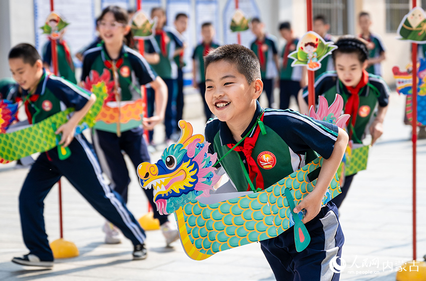 內蒙古呼和浩特市玉泉區(qū)恒昌店巷小學學生在“繽紛端午 粽享童趣”主題活動現(xiàn)場參加趣味龍舟賽。丁根厚攝