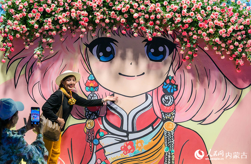 6月24日，游客在呼和浩特市玉泉區(qū)塞上老街旅游休閑街區(qū)一處花墻微景觀前拍照留影。丁根厚攝