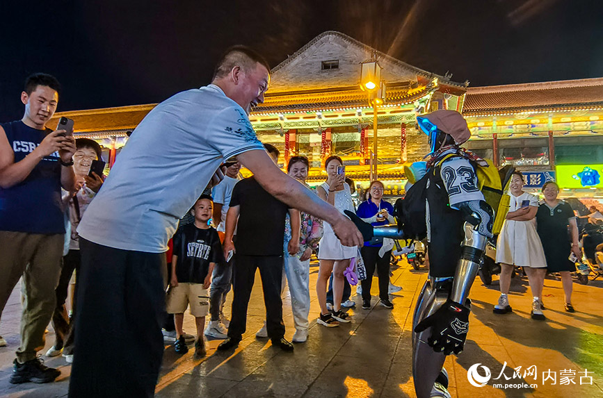 6月24日，游客在呼和浩特市玉泉區塞上老街旅游休閑街區與宇樹人型機器人互動。丁根厚攝