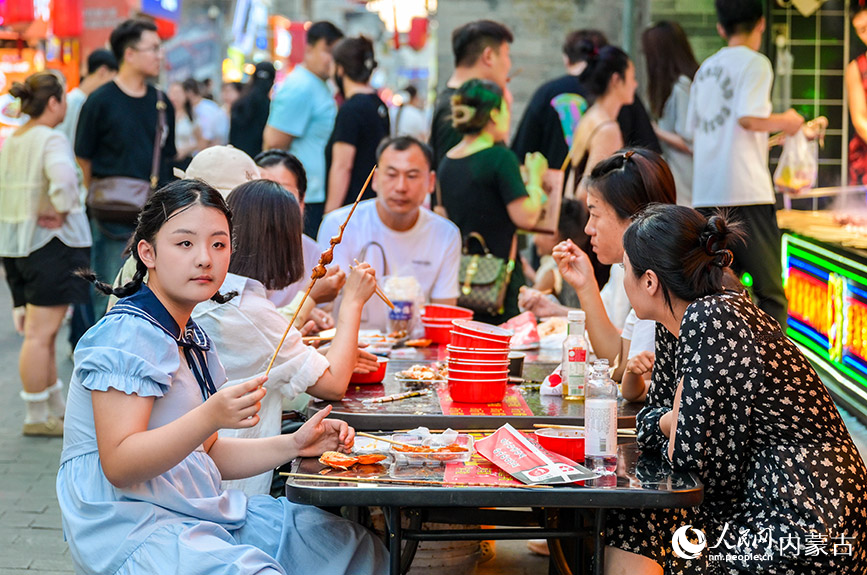 6月24日，游客在呼和浩特市玉泉區塞上老街旅游休閑街區“通順大巷夜市”品嘗特色小吃。丁根厚攝