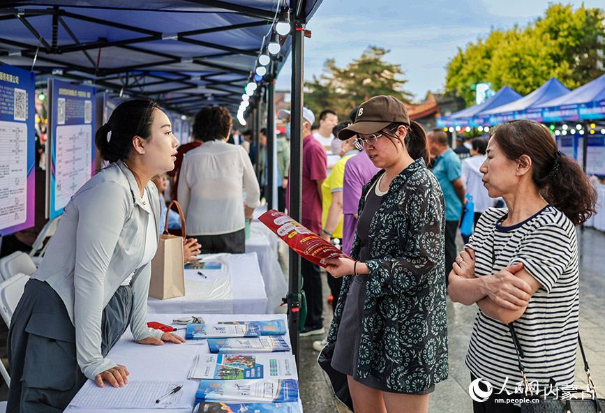 6月28日晚，招聘人員在呼和浩特市玉泉區“人才夜市”專場招聘會現場向求職者介紹崗位信息。丁根厚攝