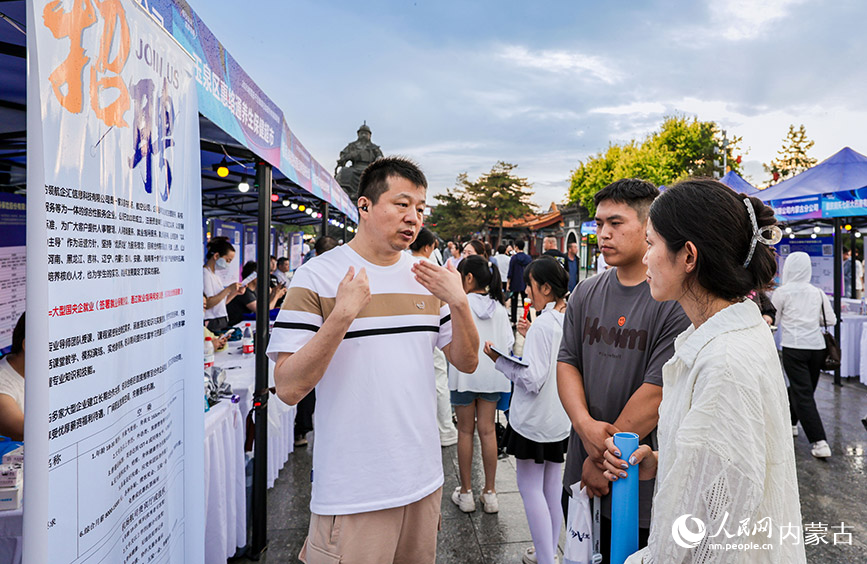 6月28日晚，招聘人員在呼和浩特市玉泉區(qū)“人才夜市”專場招聘會現(xiàn)場向求職者介紹崗位信息。丁根厚攝