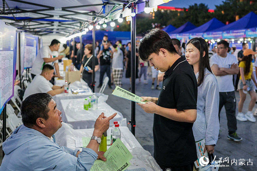 6月28日晚，招聘人員在呼和浩特市玉泉區“人才夜市”專場招聘會現場向求職者介紹崗位信息。丁根厚攝