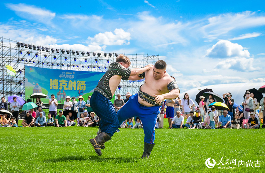 7月5日，游客在呼和浩特城市那達慕活動現場觀看搏克比賽。丁根厚攝