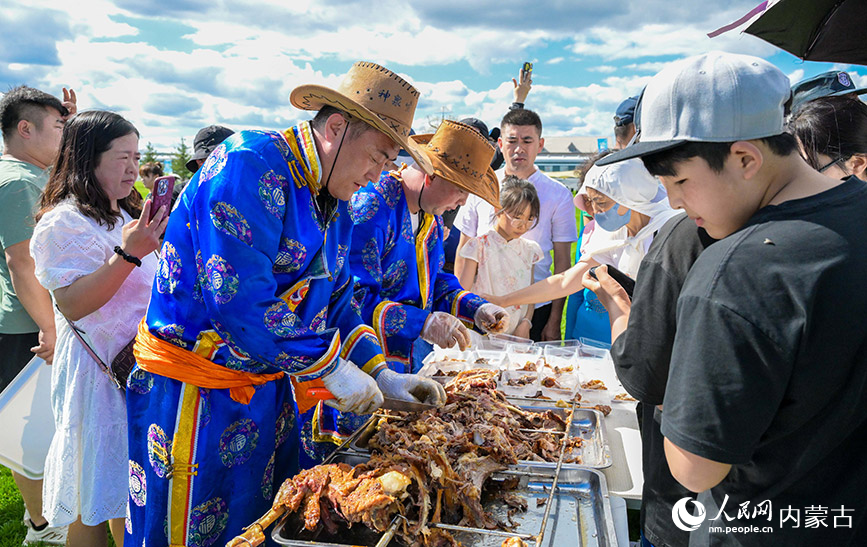 7月5日，工作人員在呼和浩特城市那達慕活動現場為游客分發烤全羊。丁根厚攝