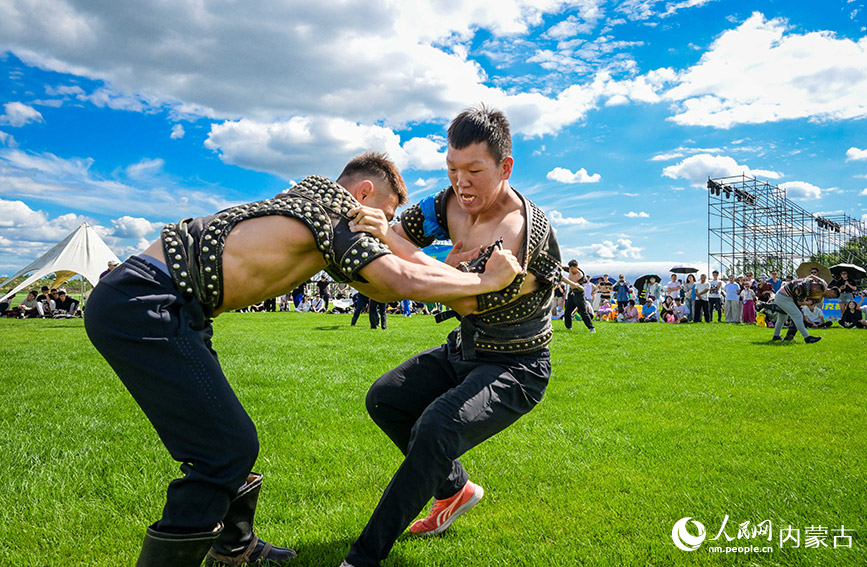 7月5日，游客在呼和浩特城市那達慕活動現場觀看搏克比賽。丁根厚攝