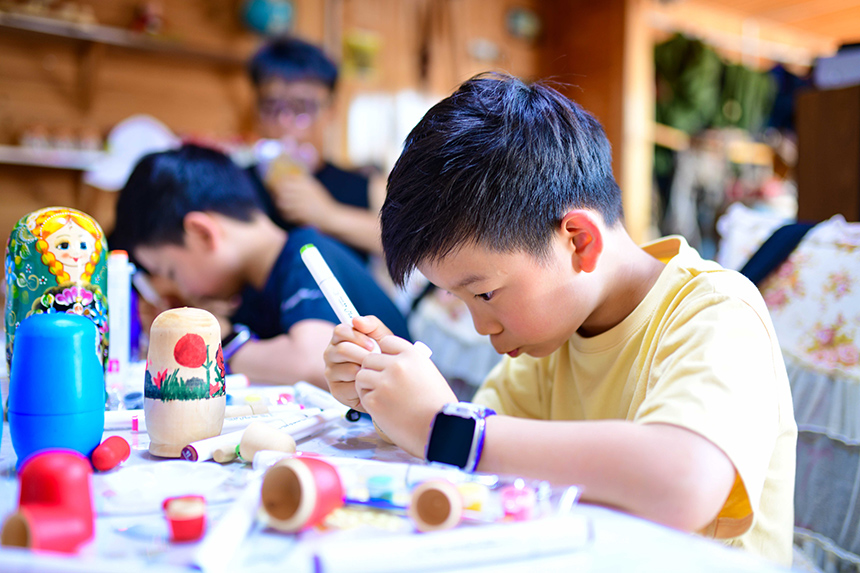 小朋友在額爾古納市恩和俄羅斯族民族鄉恩和村一戶民居里彩繪套娃。王正攝