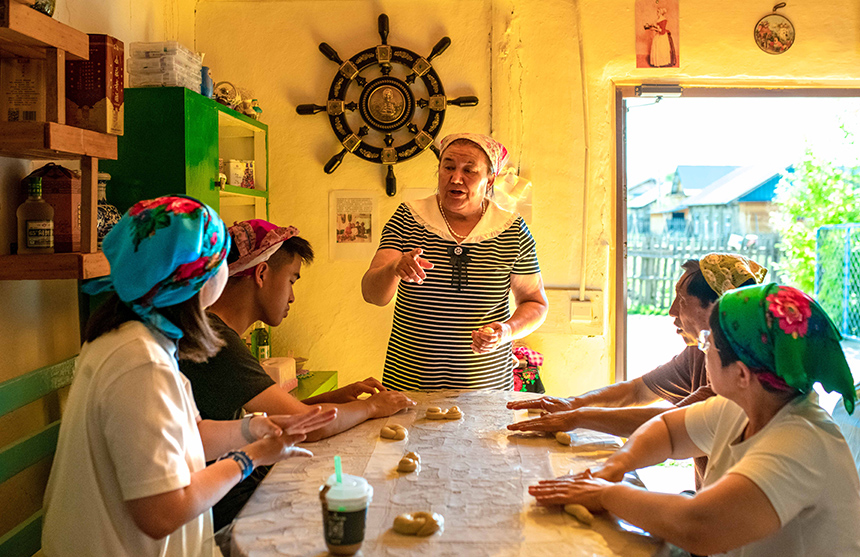 游客在額爾古納市恩和俄羅斯族民族鄉恩和村一戶民居里體驗列巴制作技藝。王正攝