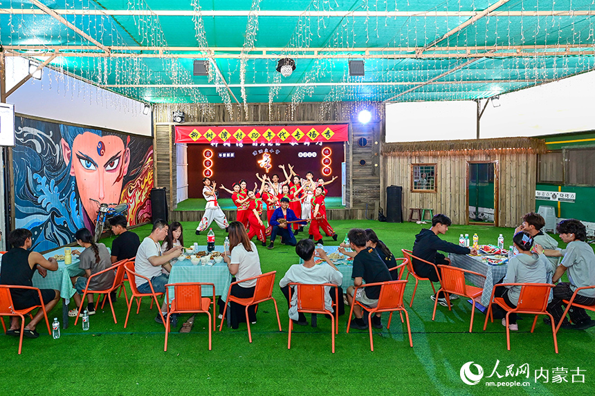 游客在鄂爾多斯市伊金霍洛旗鄂爾多斯文化產業園景區柳樹灣村觀看消夏晚會。王正攝