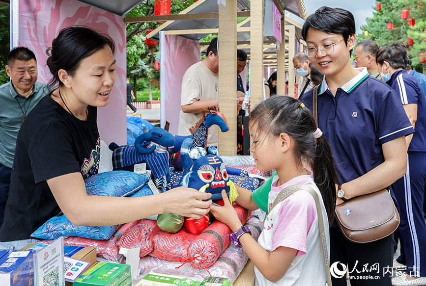 7月19日,游客在呼和浩特燒賣美食季活動現場選購布藝文創產品。丁根厚攝