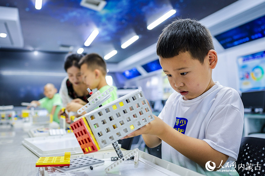 7月20日，孩子們在內蒙古呼和浩特市玉泉區青少年宮學習拼搭創意機器人。丁根厚攝