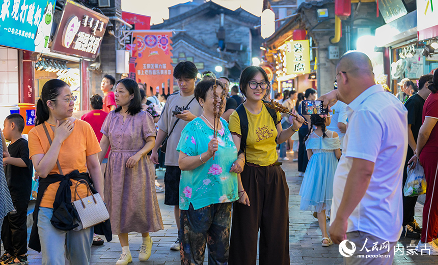 游客在呼和浩特市玉泉區(qū)塞上老街旅游休閑街區(qū)“通順大巷夜市”游玩。丁根厚攝