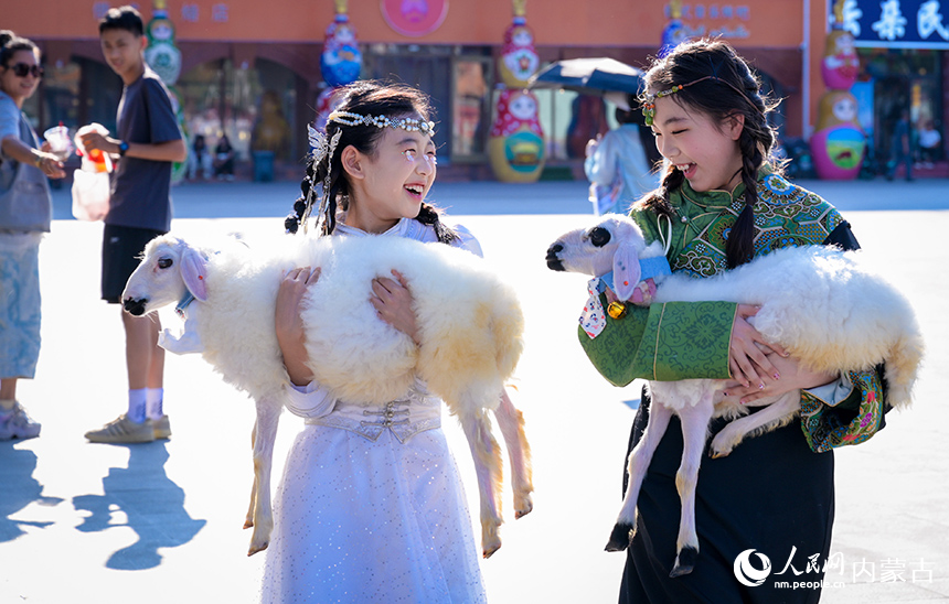 游客在呼和浩特市玉泉區(qū)塞上老街旅游休閑街區(qū)抱著小羊羔，準(zhǔn)備體驗(yàn)民族風(fēng)旅拍寫真。丁根厚攝