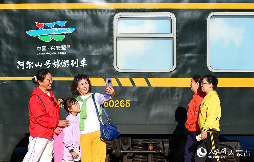 8月10日，游客在“阿爾山號”旅游專列旁留影。王正攝