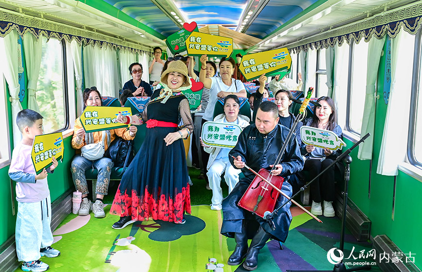 8月10日，游客與演員在“阿爾山號”旅游專列上互動。王正攝