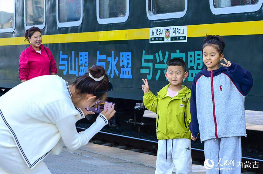 8月10日，游客在“阿爾山號”旅游專列旁留影。王正攝