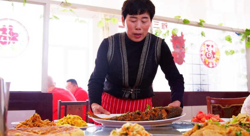 郝家窯村一家農(nóng)家樂餐廳經(jīng)營者正在為游客端上剛燉好的托縣鯉魚。王建宏攝