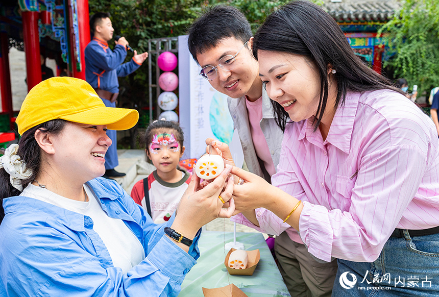 新人們在呼和浩特市玉泉區“我們的節日·七夕”主題活動現場體驗乞巧穿針項目，感受傳統民俗文化魅力。丁根厚攝