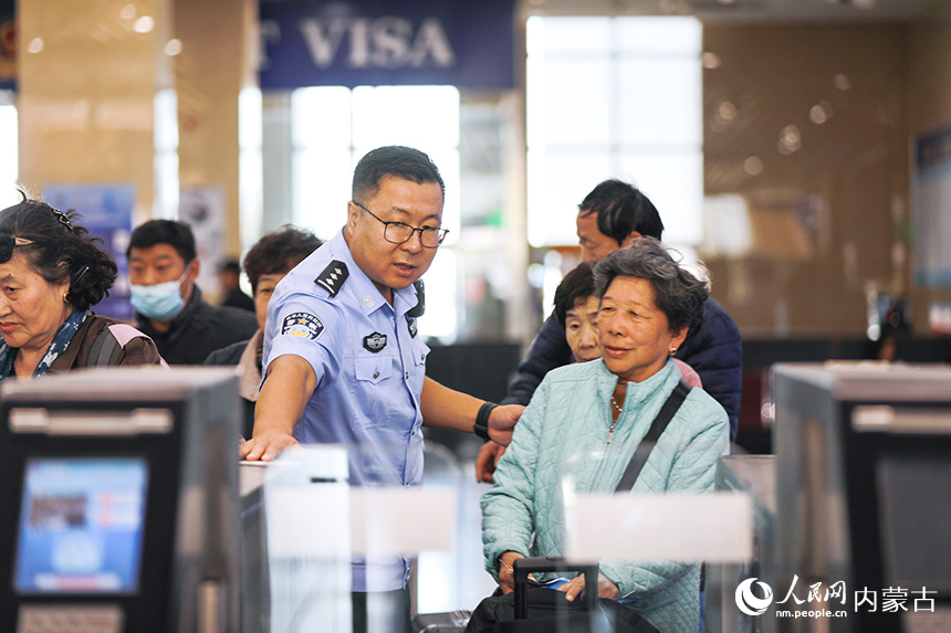 二連出入境邊防檢查站移民管理警察協助老年旅客辦理通關手續。郭鵬杰攝