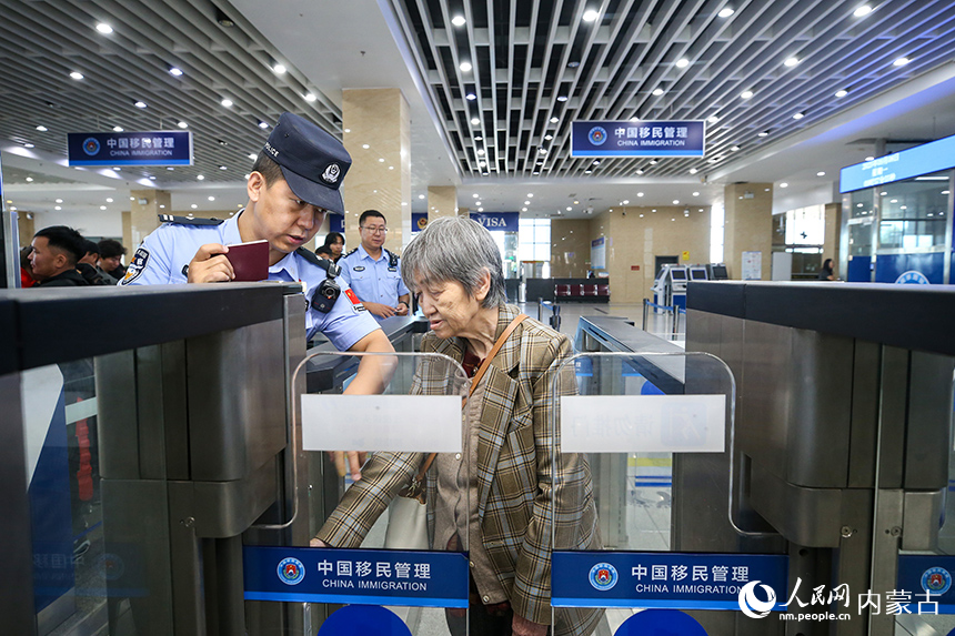 二連出入境邊防檢查站移民管理警察協助老年旅客辦理通關手續。郭鵬杰攝