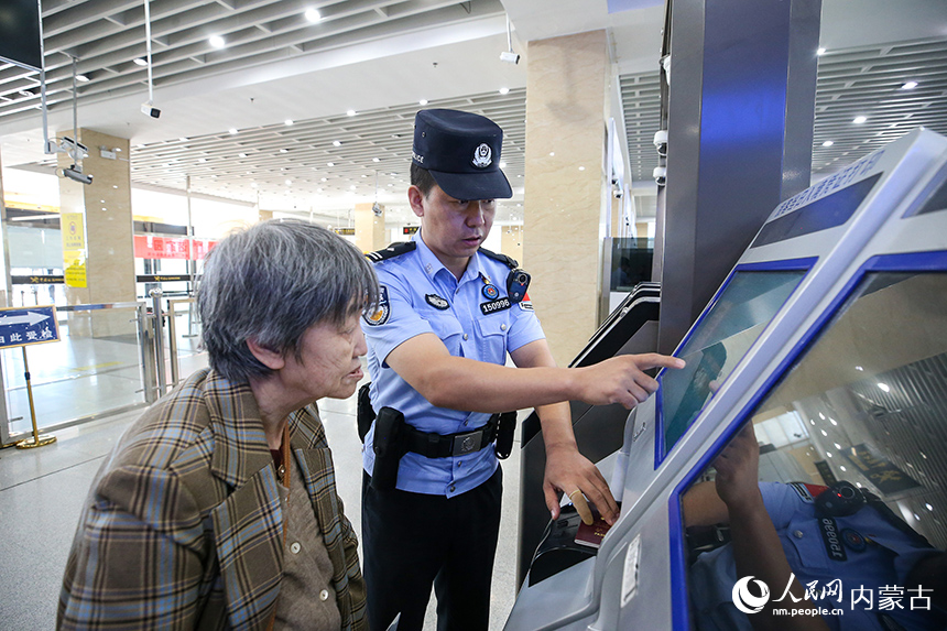 二連出入境邊防檢查站移民管理警察協助老年旅客辦理通關手續。郭鵬杰攝