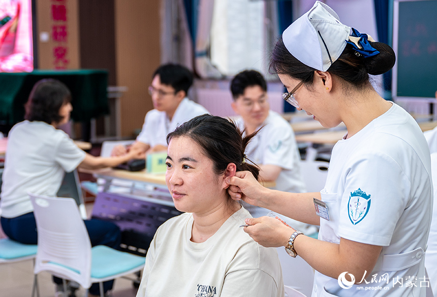 醫護人員在呼和浩特市玉泉區小召小學為老師們做耳穴貼壓治療。丁根厚攝