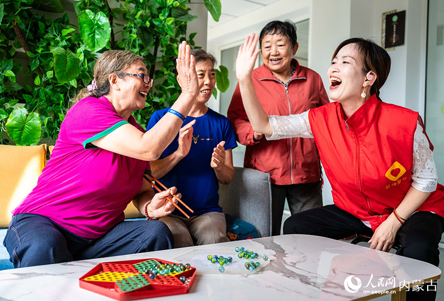 9月11日，志愿者和老人們在呼和浩特市玉泉區石東路街道居家和社區養老服務綜合體一起玩夾彈珠游戲。丁根厚攝