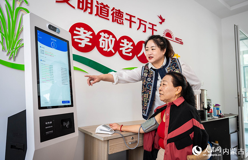 9月11日,工作人員在呼和浩特市玉泉區(qū)石東路街道居家和社區(qū)養(yǎng)老服務(wù)綜合體協(xié)助老人使用健康管理綜合機(jī)測(cè)血壓。丁根厚攝