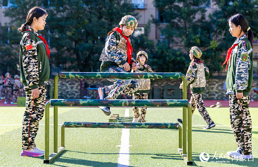 內(nèi)蒙古呼和浩特市玉泉區(qū)五塔寺東街小學學生在“心系國防 強國有我”主題教育活動現(xiàn)場參加跨越高低橫木項目的比拼。丁根厚攝
